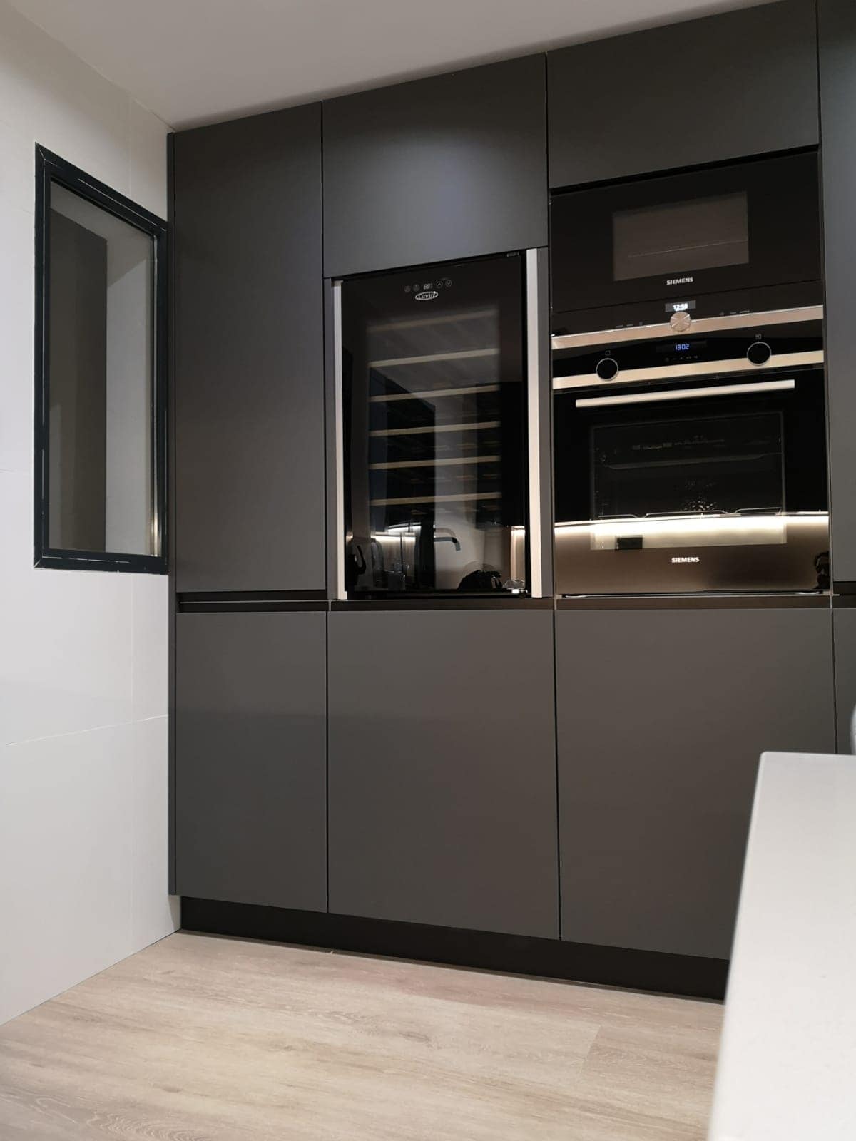 Muebles de cocina grises con vinoteca, horno y microondas integrados