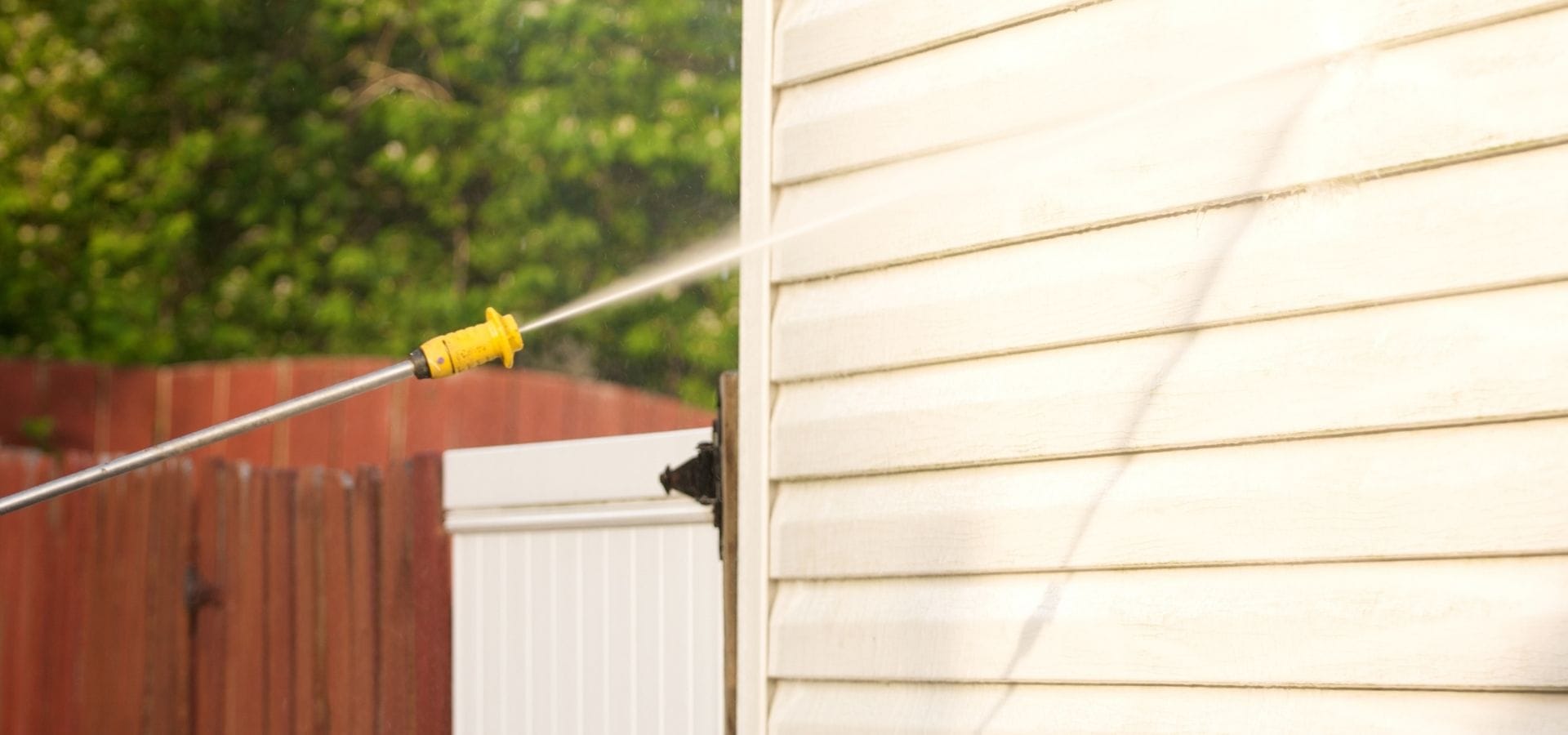 Chorro de agua a presión limpiando el revestimiento blanco de una pared exterior