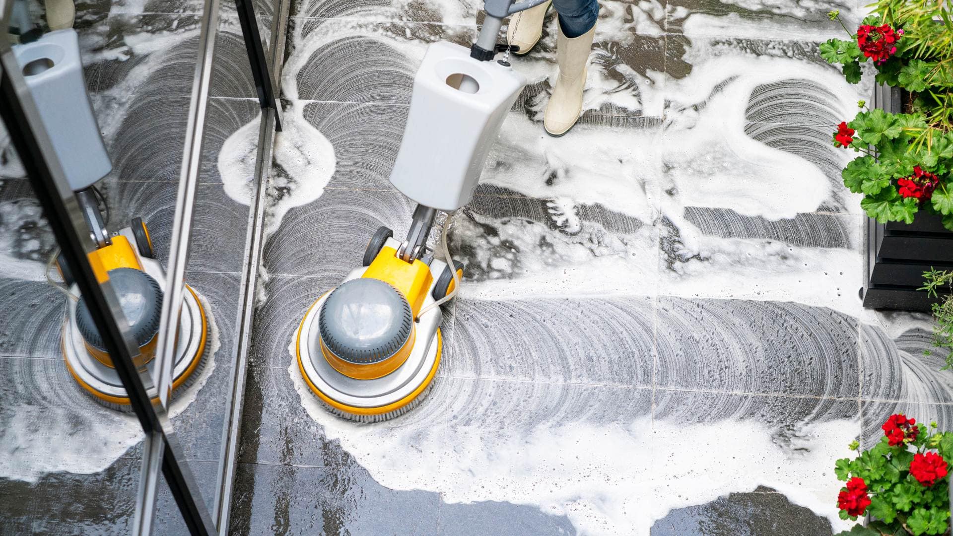 Máquina rotativa puliendo un suelo de piedra gris con espuma abrasiva